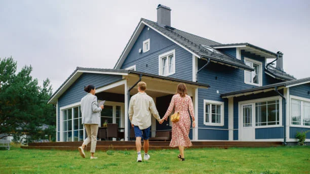 Agent walking a couple toward a blue house