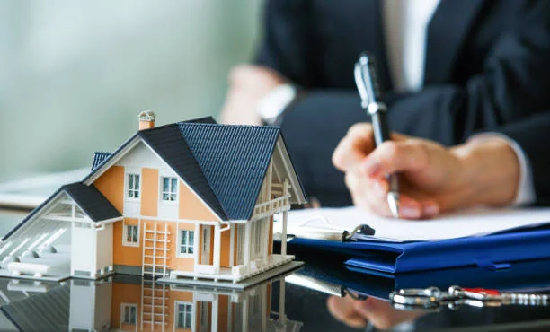 Model house next to a person signing papers