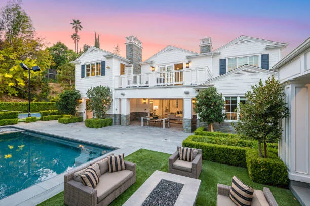 White luxury home with a pool and patio at sunset